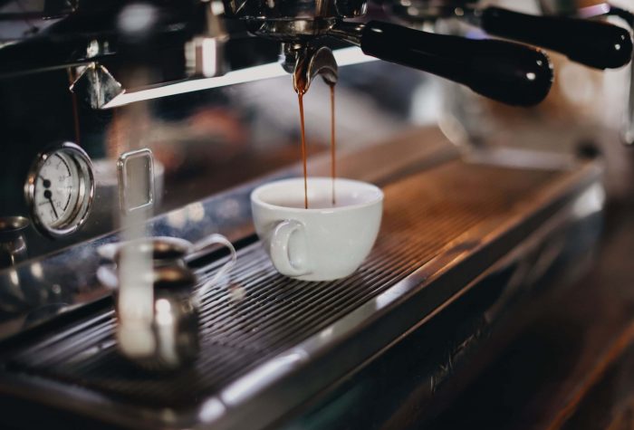 A photo of a large commercial espresso machine pouring coffee into a small espresso cup