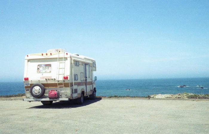 A photo of an RV parked on top of a hill overlooking the ocean. It's a beutiful day with crisp blue skies