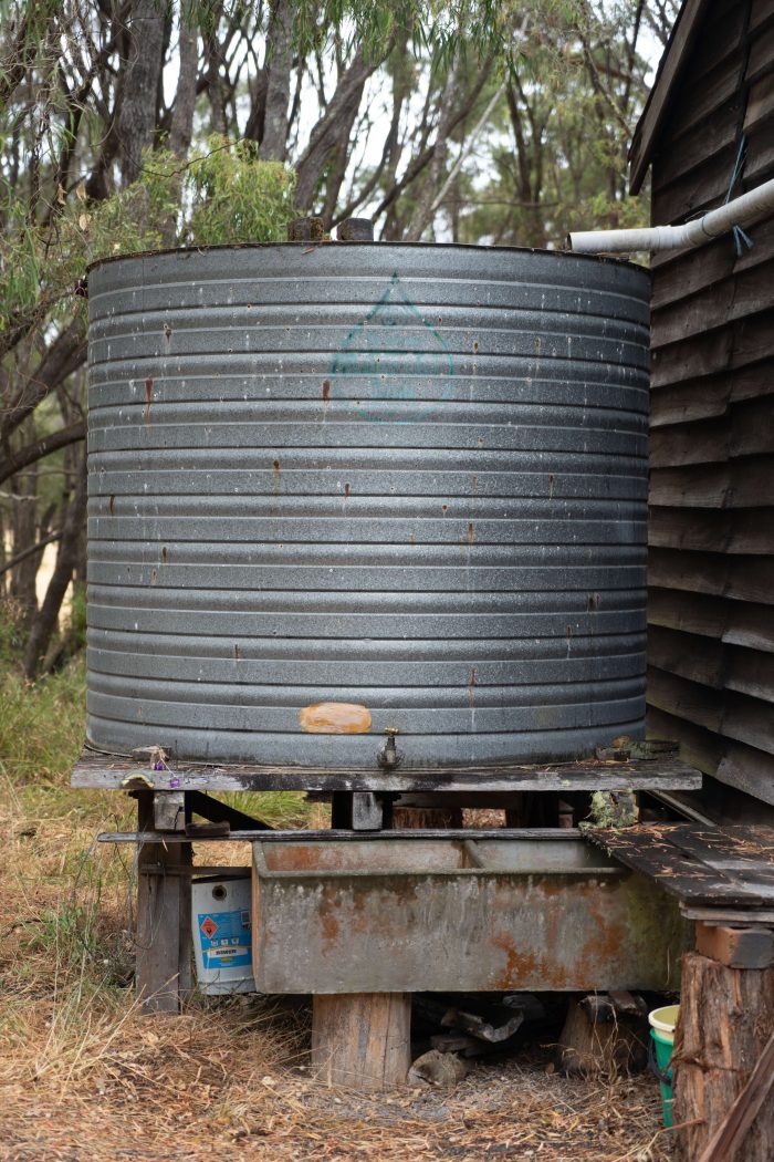 A photo of an old metal grey water tank on timber stilts