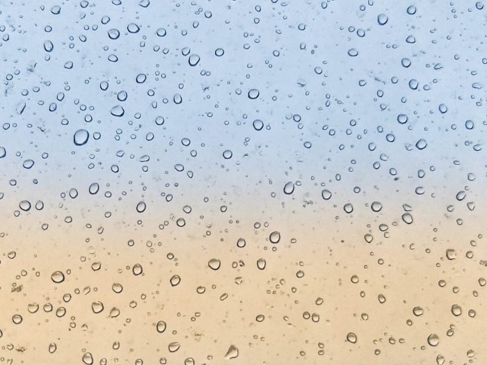 A photo of water spots on a window with a blue background