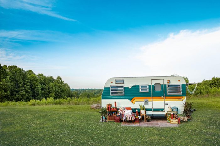 An image of a cute white, green, and yellow caravan parked in a field.