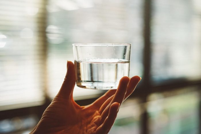 An image of a woman's hand holding a glass of water
