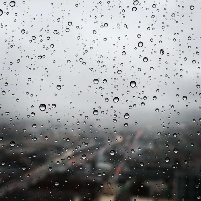 An image of rain falling against a glass window. The water contained within rain drops is acidic and may need calcite treatment